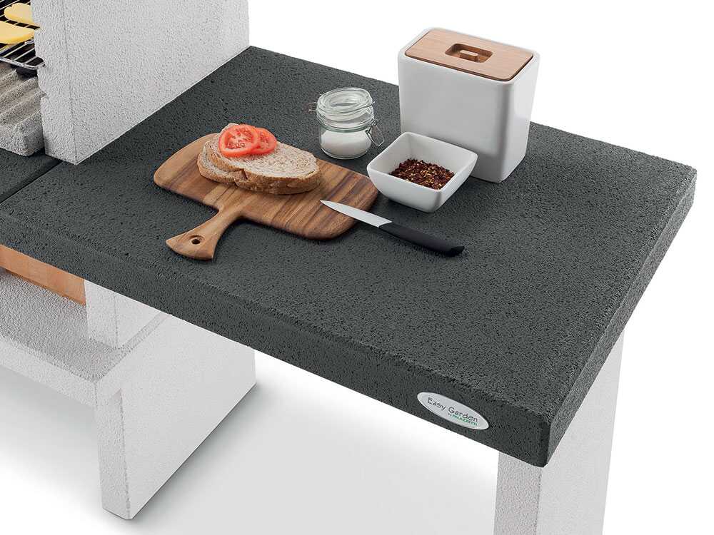 Barbecue à bois et charbon Palazzetti Ravello en ciment réfractaire avec grille réglable 68 x 40 cm, espaces de rangement et finitions Marmotech. Idéal pour 10 à 14 personnes.